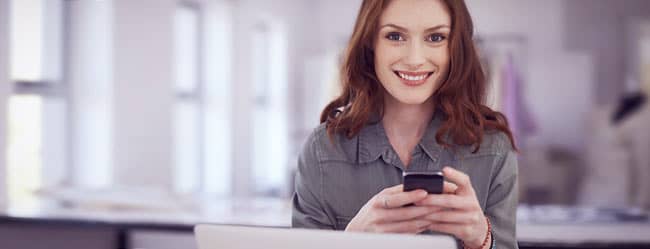 Frau am Handy informiert sich über ElitePartner-Kosten
