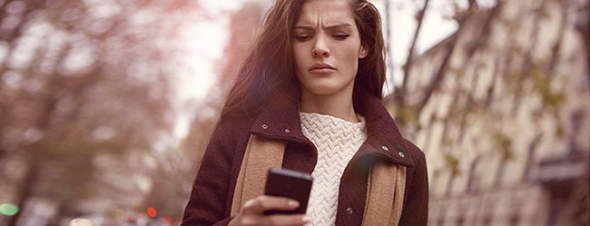 Frau schaut verwirrt in Ihr Handy weil sie nicht weiß wie sie einen Korb geben soll