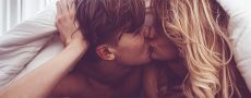 Mann und Frau unter der Bettdecke küssen sich leidenschaftlich als Symbolbild für Sexualität in der Partnerschaft