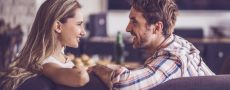 Frau und Mann sitzen sich auf Couch gegenüber und versuchen ihr Gegenüber zwischen Anspruch und Wirklichkeit zu wählen
