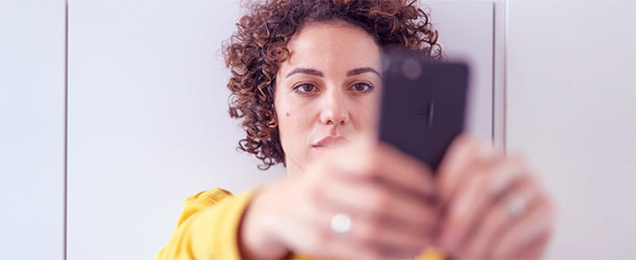 Frau ist schaut gefühlskalt auf ihr Handy