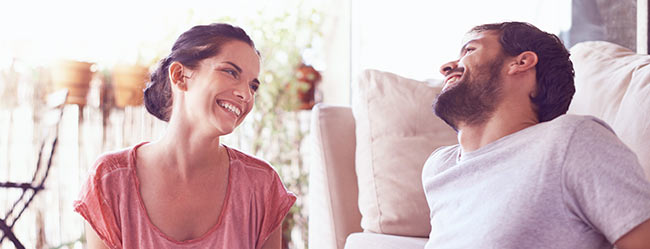 Mann und Frau in glücklicher Beziehung heute lachen sich glücklich im Wohnzimmer an