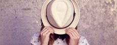 Symbolbid von Traumfrau durch Frau die ihr Aussehen hinter einem Hut versteckt