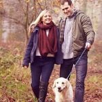 Frau und Mann spazieren mit Hund, als Beispiel für Date Ideen