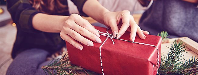 Frau packt Weihnachtsgeschenk für ihren Partner ein und hat darauf geachtet nichts Falsches zu kaufen