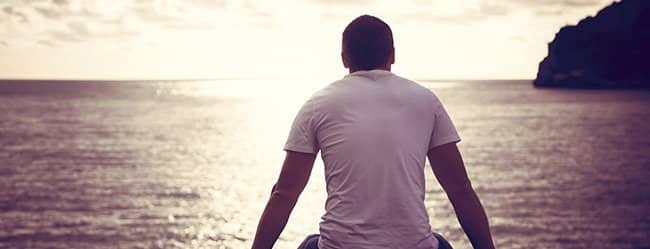 Mann sitzt allein am Meer und denkt über Beziehungsunfähigkeit nach