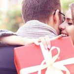 Date Geschenk: Frau umarmt Mann und hat Geschenk in der Hand