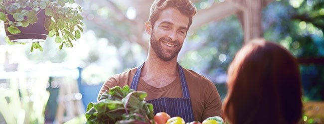 Mann beim Flirten lernen am Gemüsemarkt mit Obstkiste in der Hand