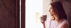 Neurotiker: Frau trinkt Kaffee und schaut aus dem Fenster