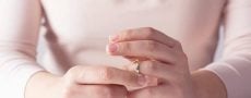 Hände einer Frau, die mit Ring am Finger spielt und sich fragt: "Warum heiraten?"