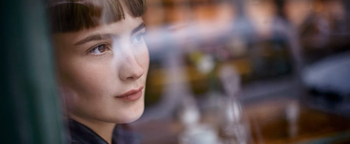 Frau schaut aus dem Fenster - sie hat Angst alleine zu sein